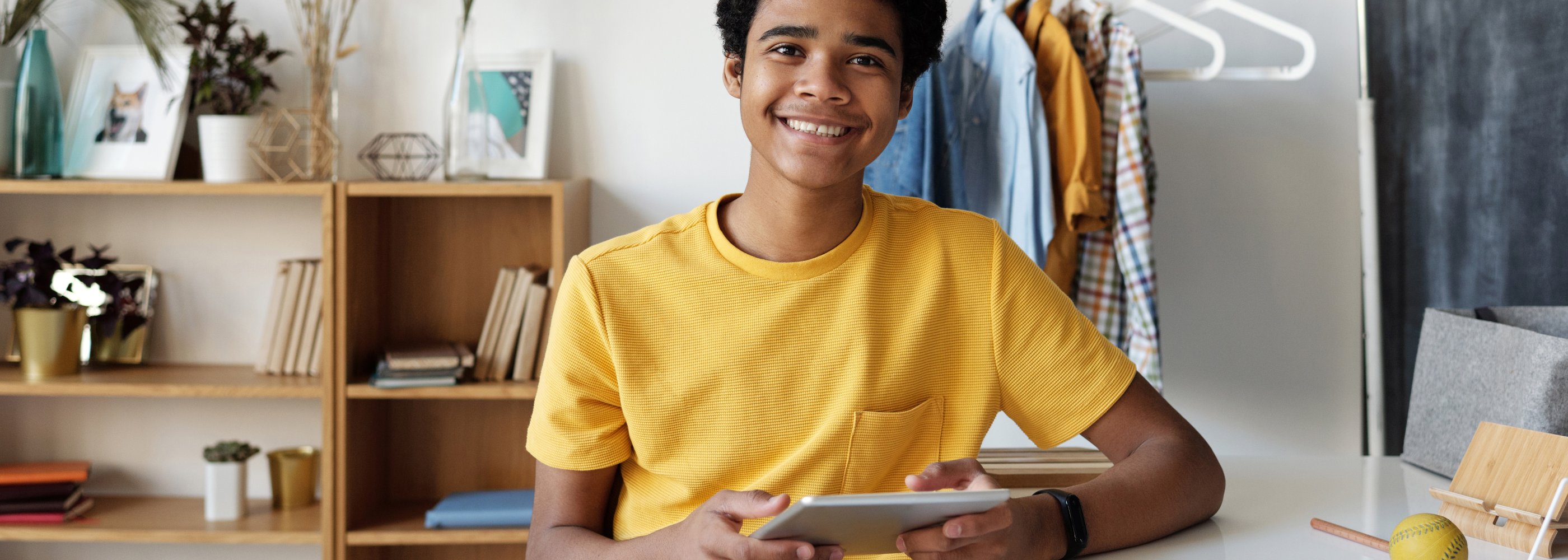 boy in yellow shirt smiling with technology